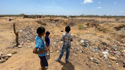 Refugee settlement in Colombia - boys standing outside near pile of trash - War Child