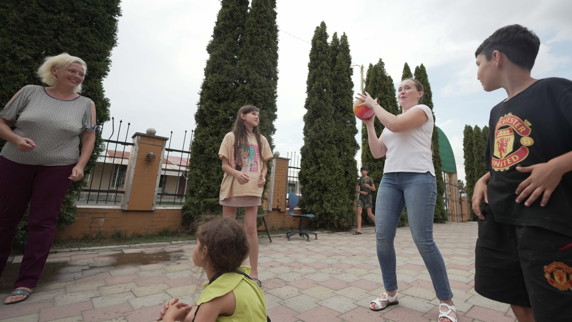 Two women who run the BLAHO shelter playing with children and a ball
